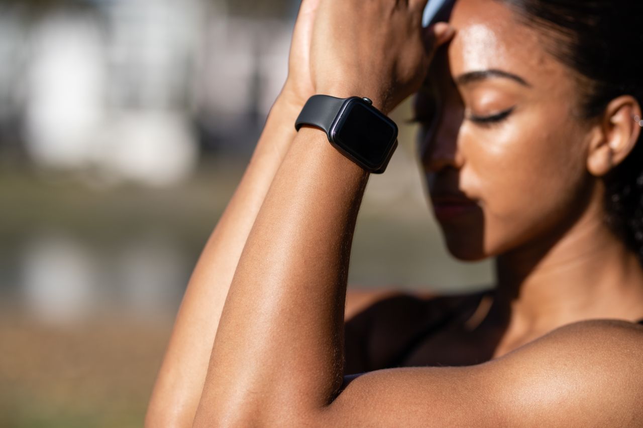 Close-up of a woman practicing yoga with a smartwatch outdoors.